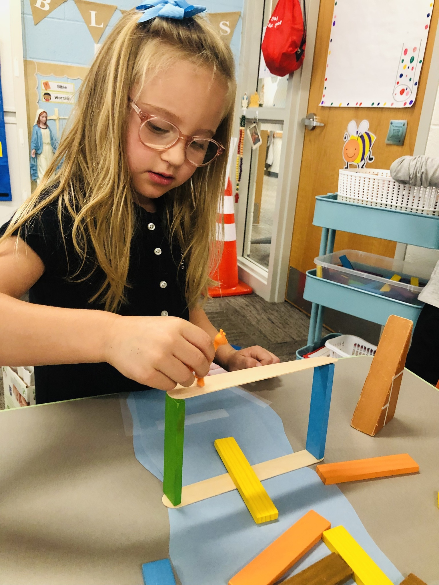 Young 5 student testing the integrity of her bridge.  Students made a plan, built a bridge, and tested their bridge.