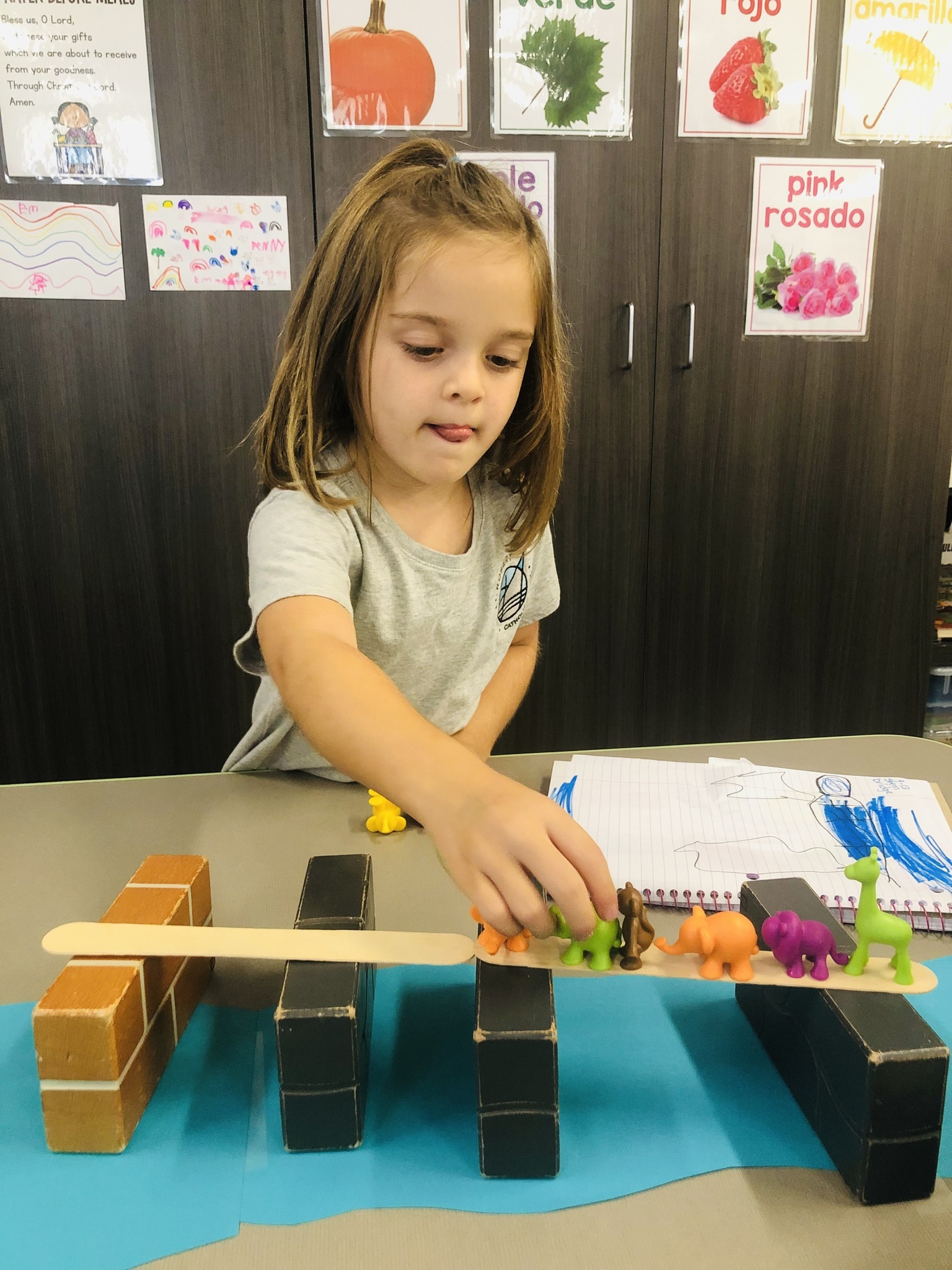 Young 5 student carefully testing her bridge.